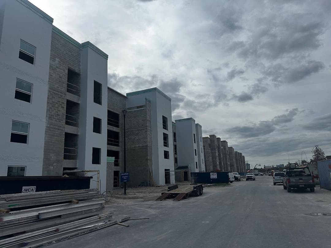 Newly constructed apartment building with cloudy sky and construction materials on site.