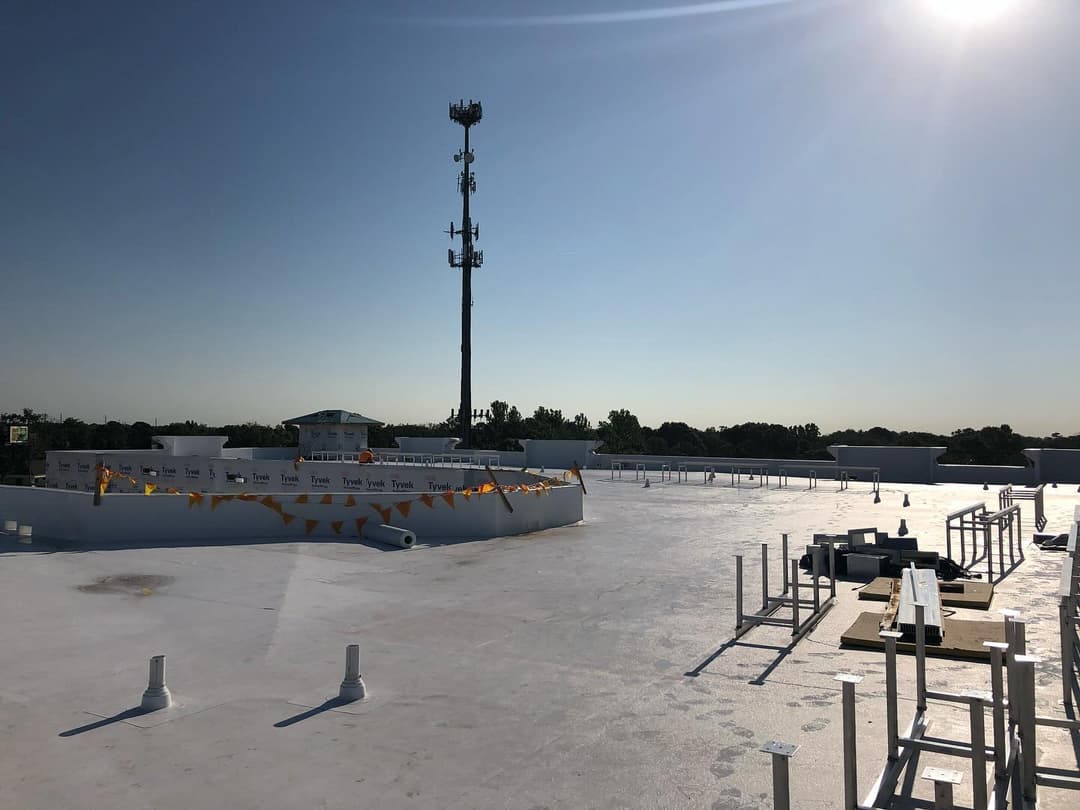 Rooftop view showcasing cell tower and construction materials under clear blue sky.